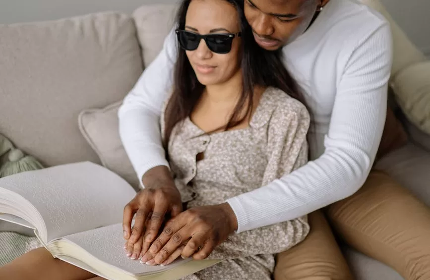 a man helping a woman read a braille book